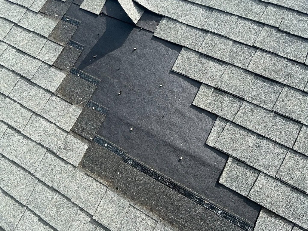 Missing shingles and exposed underlayment before roof replacement