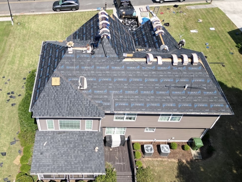 Roof replacement in progress with synthetic underlayment and shingle installation